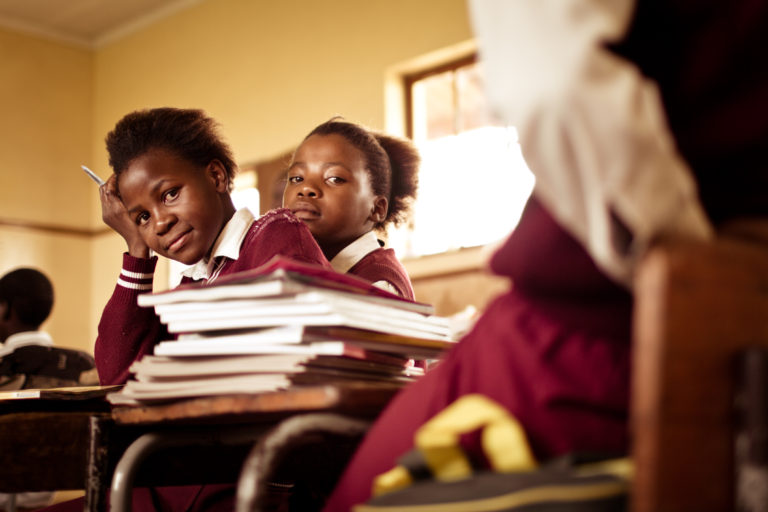 South African girl (from the Xhosa tribe) works on her studies at an old worn desk in a class room in the Transkei region of rural South Africa.